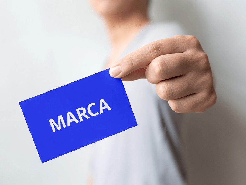 Pessoa segurando um cartão na ponta do dedo escrito "marca"